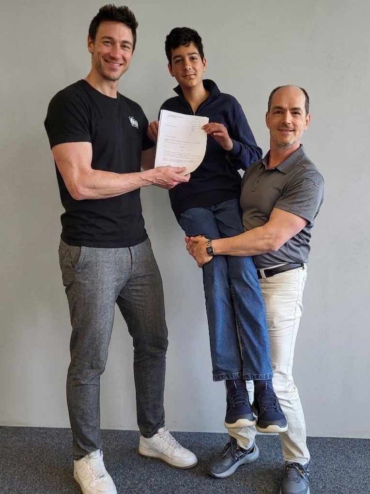 Dilan Baban erhält von Mathelehrer Christian Greschik und stellvertretendem Schulleiter Philipp Freykowski die Urkunde