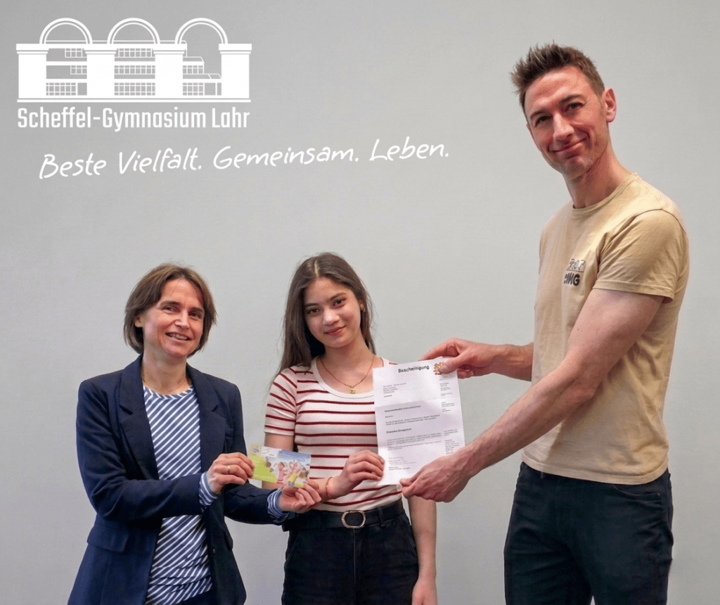 Die Scheffel Schülerin Eylül Oktay erhält von Deutschlehrerin Bettina Hölscher und stellvertretendem Schulleiter Philipp Freykowski die Urkunde und den Preis für ihren 3. Platz beim Zischup Wettbewerb.