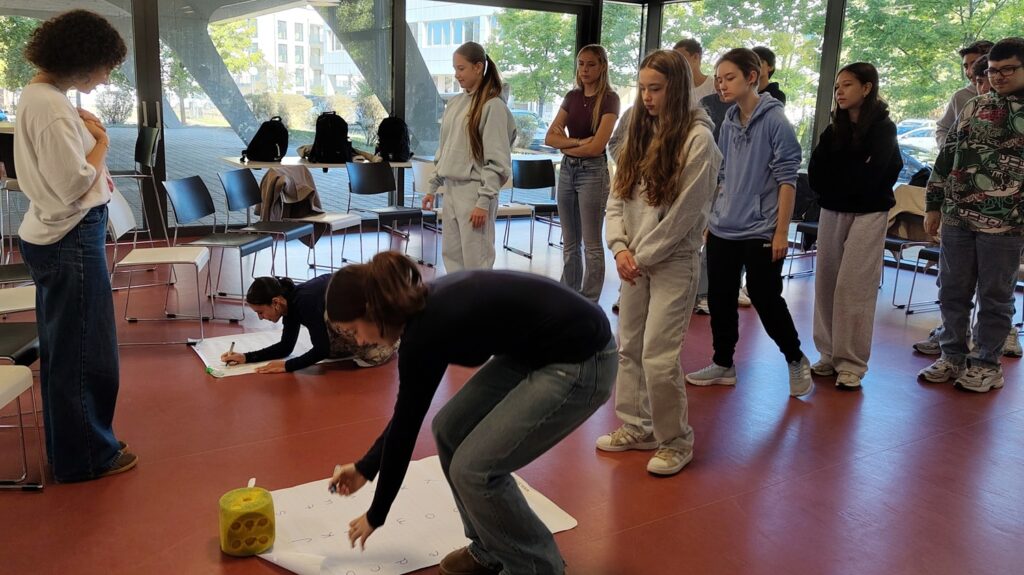 260928FranceMobil3 Schüler:innen schreiben in zwei Reihen Wörter auf Plakate