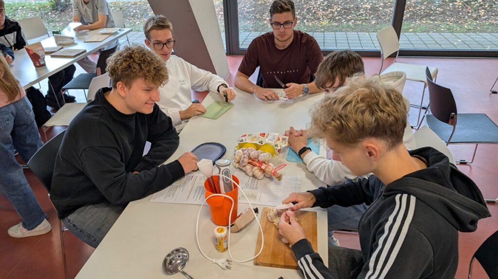 261014Barcelona1 Schüler sitzen am Tisch und schneiden Knoblauch